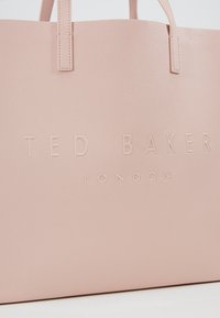Lichtroze totebag van gestructureerd synthetisch materiaal, met het reliëf merklogo "TED BAKER LONDON" aan de voorkant en twee handvaten.