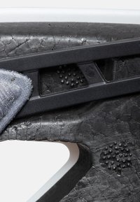 Svart texturerat material med matt yta har ett upphöjt prickmönster och en slät grå tygdetalj, integrerat med en svart plastkomponent.