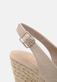 Sandalo wedge in pelle beige con una robusta fascia con fibbia quadrata, tacco in juta intrecciata e soletta morbida e testurizzata.