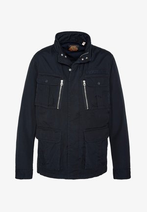 Giacca militare di colore blu navy, con colletto alto, due tasche sul petto con pattina, due tasche inferiori e dettagli in zip argentata.