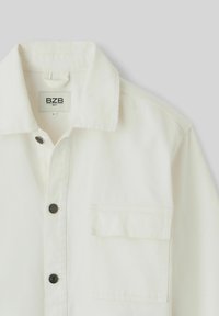 Chemise blanche à boutons avec col, poche poitrine simple avec rabat et boutons noirs, taille large de la marque BZB.