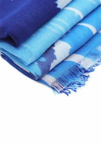 Foulard blu a motivi impilati insieme, con tessuto morbido, varie tonalità di blu e bordi frangiati per un dettaglio di texture.