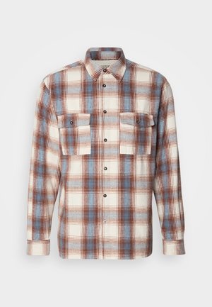 Geruite blouse in roomkleur, bruin en lichtblauw. Lange mouwen, knoopsluiting aan de voorkant met twee borstzakken en zwarte knoopaccenten. Zachte textuur.