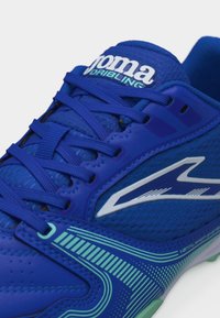 Gros plan sur une chaussure de football bleue Joma Dribling avec des lacets, un mesh de ventilation et un logo blanc sur le côté.