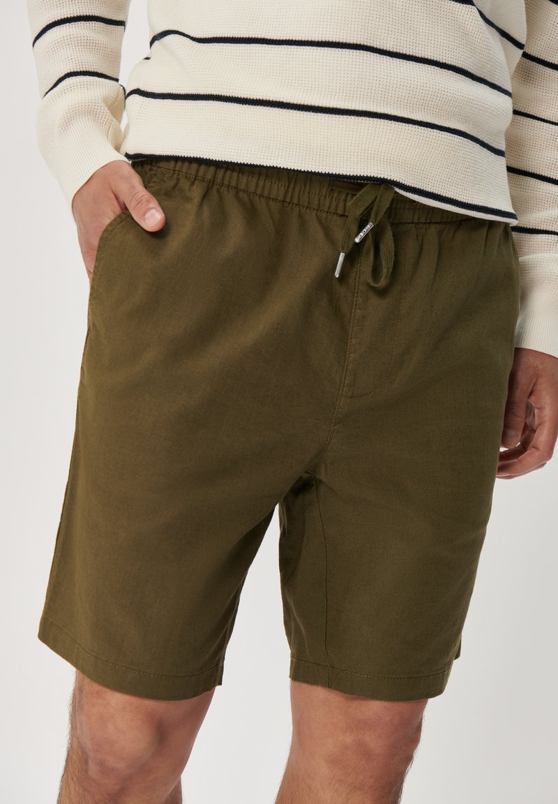 Olive green cotton shorts with an elastic waistband and drawstring, featuring side pockets and a straight leg cut.