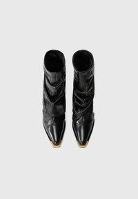 Black leather slouchy boots with pointed toes and gold metal tips, shown from above on a plain light background.