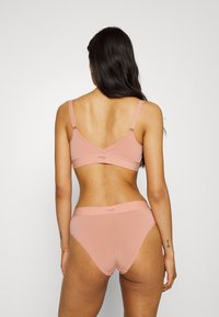 Light pink bra and high-waisted panties made from soft fabric. The design features adjustable straps and a smooth texture.