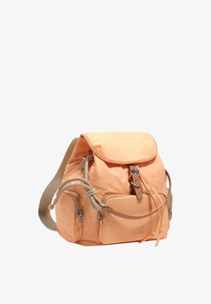 Jasnopomarańczowy plecak z przednimi i bocznymi kieszeniami na suwak, zamknięciem na troczek, klapką na klamrę oraz beżowymi paskami na ramiona.