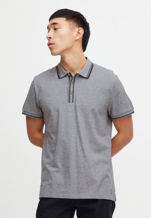 Grå polo-shirt med krave og to knapper, der har sorte stribede detaljer på kraven og ærmerne. Blødt stof.