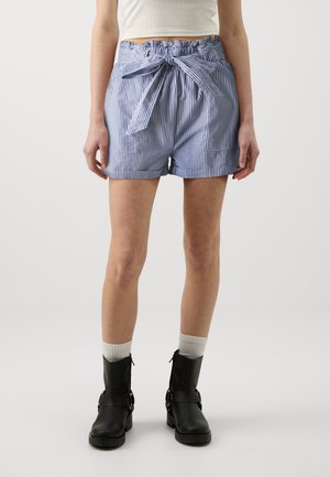 Shorts rayés bleus et blancs avec une taille élastique et une ceinture nouée. Tissu lisse, coupe ajustée, bords ourlés, associés à des bottes noires.