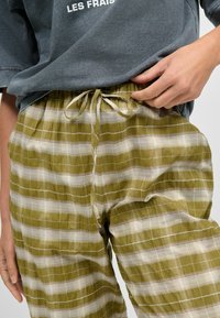 Groene en witte geruite pyjamabroek met een elastische tailleband en een trekkoord. Gemaakt van een lichte stof, met een ontspannen pasvorm en zijzakken.