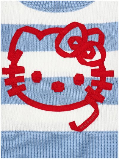 Visage rouge de Hello Kitty avec un nœud, délimité par un ruban, sur un tissu tricoté à rayures bleues et blanches.