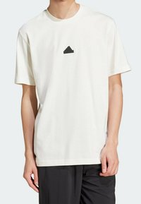 Camiseta de algodón blanca con mangas cortas y escote redondo. Presenta un logo de pirámide negra en el pecho. Textura suave y lisa.