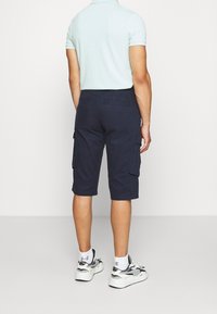 Shorts cargo navy en matériau léger, dotés de poches latérales et arrière, avec une coupe au genou et une coupe décontractée.