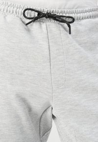 Gray sweatpants made of soft cotton blend fabric, featuring an elastic waistband with a black drawstring and side pockets.