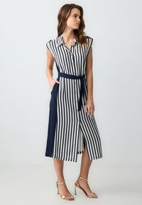 Gestreiftes Hemdkleid in Marineblau und Weiß, mit durchgehender Knopfleiste, kurzen Ärmeln, Taillengürtel und seitlichen Taschen. Glatte Stoffoberfläche.