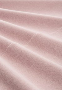 Tissu rose doux avec une texture lisse, présentant de légères plis et une apparence légère, idéal pour les vêtements ou le revêtement.