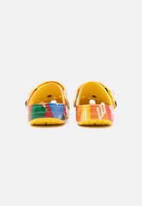 Sabots colorés avec une base jaune et des motifs multicolores vibrants. Arrière arrondi, perforations et design confortable.