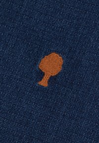 Marine stof met een gestructureerde textuur, uitgerust met een geborduurd bruin boomontwerp. De boom is gecentreerd en heeft een gestileerde vorm.