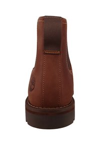 Botín de cuero marrón hasta el tobillo con un acabado texturizado, que presenta una lengüeta, costuras elevadas y una suela de madera oscura con un detalle del logo.
