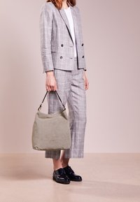 Lichtgroene suède hobo-tas met een enkele leren band, gecombineerd met een grijs geruit pak, bestaande uit een double-breasted blazer en enkellange broek.