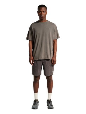 Mann, der nach vorne schaut, trägt ein locker sitzendes graues T-Shirt, dunkelgraue Shorts mit Seitentasche, weiße Socken und graue Sneakers.