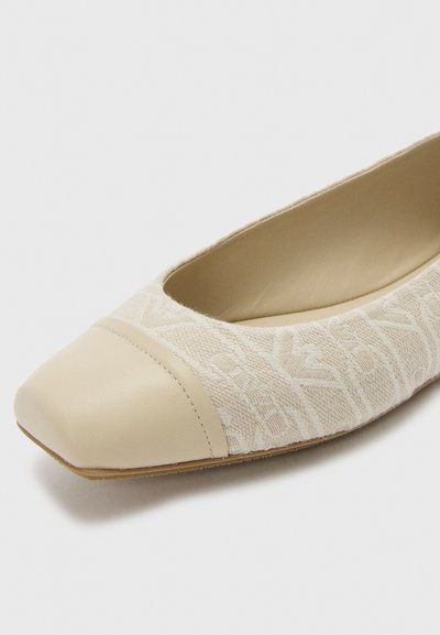 Scarpe piatte beige con tomaia in tessuto texturizzato e punta in pelle liscia. Presentano una forma arrotondata e un design a profilo basso.