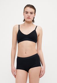 Fekete pamut bralette állítható pántokkal, V-kivágással és logós pánttal, párosítva illeszkedő fekete boyshortsokkal, puha derékpánttal.