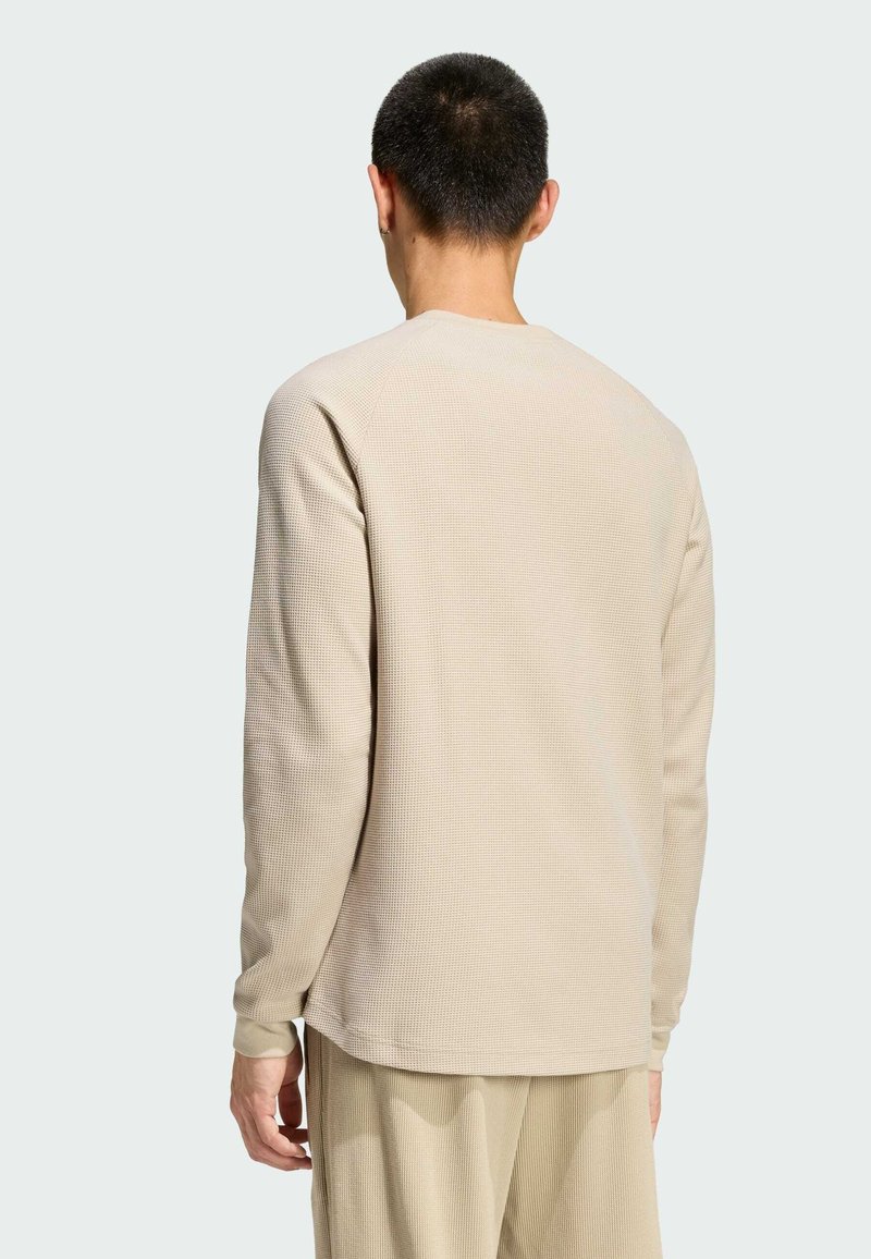 Beige ribbed long-sleeve shirt with a crew neck and raglan sleeves, featuring subtle texture and a straight hem. Designed for a relaxed fit.