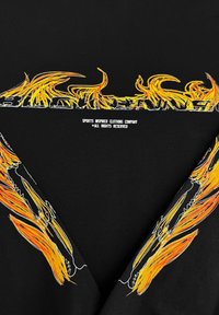 Zwarte t-shirt met heldere oranje en gele vlamgraphics en witte tekst "SPORTINSPIREDE KLEDINGBEDRIJF" gecentreerd eronder.