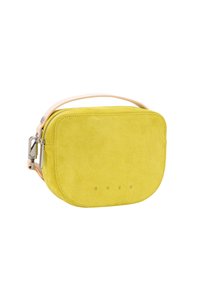 Gele suède crossbodytas met afgeronde randen, een lichte leren riem en een geperst merklogo aan de voorkant. Soepele textuur en minimalistisch ontwerp.