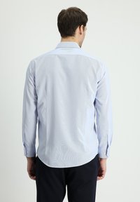 Camicia azzurro chiaro a maniche lunghe con colletto a punta, tessuto testurizzato e polsini con singolo bottone. Orlo arrotondato e dettagli del motivo sottili.