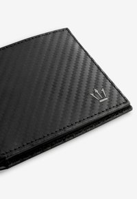 Portefeuille en fibre de carbone noir avec un motif texturé, présentant un accent de logo métallique subtil. Les bords sont cousus pour une durabilité accrue.