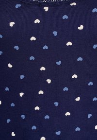 Námořnický pruhovaný top bez rukávů s vzorem malých srdcí v odstínech modré a bílé. Design zahrnuje jemné texturové detaily.