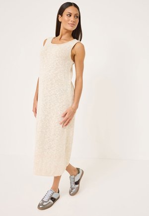 Knit beige sleeveless maxi dress with a scoop neck; worn with gray and blue sneakers featuring metallic accents and textured detail.