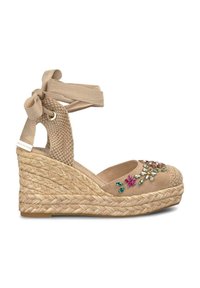Beige espadrille sleehak met een jute zool, stoffen enkelbandjes en florale edelsteenversieringen op de teen. Geweven ontwerp aan de achterkant.