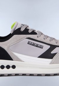 Sneaker grigio e nero con tomaia in suede testurizzato, dettagli bianchi, una linguetta sul tallone verde neon e suola in gomma con disegni circolari.