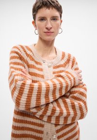 Cardigan a righe in beige e ruggine, texture lavorata a maglia, scollatura rotonda, chiusura frontale con bottoni e accentuazione in perla, maniche lunghe, vestibilità rilassata.