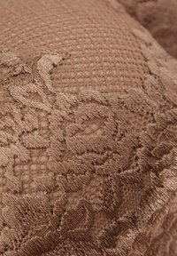 Texturovaný polštářek v tlumené hnědé barvě s květinovým krajkovým vzorem a kontrastním síťovaným povrchem, zdůrazňující bohaté textilní detaily.