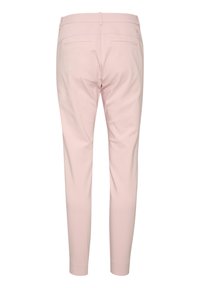 Light pink tailored trousers with a smooth texture, two back pockets, and a slim fit design tapering at the ankle.