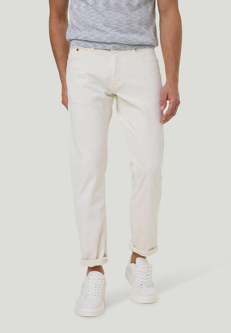 Witte denim jeans met een rechte pasvorm, voorzien van opgerolde manchetten en een medium hoge taille, gecombineerd met witte sneakers en een grijze trui.