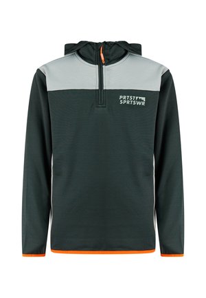Jongen die een donkergroene en lichtgrijze sportjas met oranje rand en bijpassende broek draagt, staat en kijkt naar links.