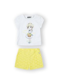 Camiseta blanca de algodón con una ilustración de chica impresa y texto; combinada con pantalones cortos amarillos con un patrón texturizado de puntos y cintura elástica.