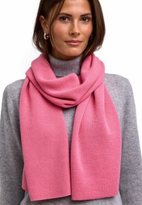 Roze geribbelde sjaal van zacht materiaal, om de nek gedrapeerd, gecombineerd met een lichtgrijze coltrui. Eenvoudig en elegant ontwerp.