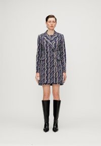 Rochie scurtă cu modele în nuanțe de albastru, alb și violet, cu mâneci lungi și buzunare. Asortată cu cizme înalte, negre, cu vârf ascuțit. Textură netedă.