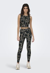 Zwarte sportieve crop top en leggings met geometrische tan patronen. De stof heeft een gladde, rekbare textuur, geschikt voor sportkleding.