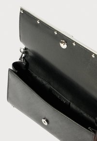 Portafoglio in pelle nera con una texture liscia, chiusura a scatto in argento e slot per carte visibili all'interno. Nome del marchio impresso all'interno.