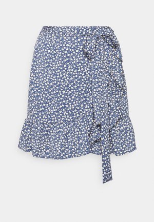 Jupe portefeuille bleue avec un motif floral blanc, avec un lien sur le côté à la taille et un ourlet volé, présentée sur un fond blanc uni.
