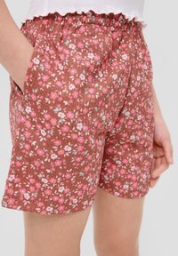 Shorts floraux marron avec un tissu texturé orné de fleurs roses et bleu clair, une taille élastique et des poches latérales.
