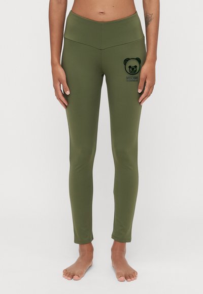 Leggings vert olive en tissu extensible, avec un logo d'ours brodé et le nom de la marque sur le côté gauche. Texture lisse.